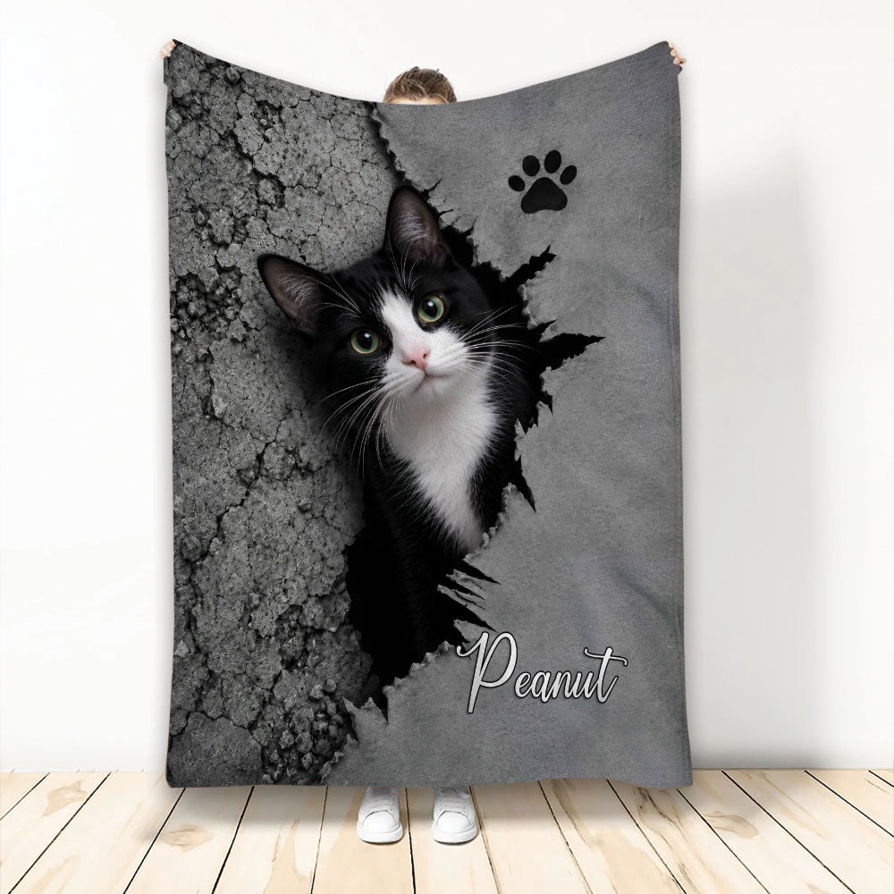 Tuxedo cat blanket with a black-and-white cat emerging through a cracked gray wall