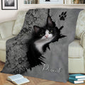 Black-and-white tuxedo cat blanket styled across a sofa with paw print artwork