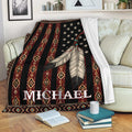 American Native-inspired throw blanket displayed on a sofa with feather artwork and patterned geometric stripes