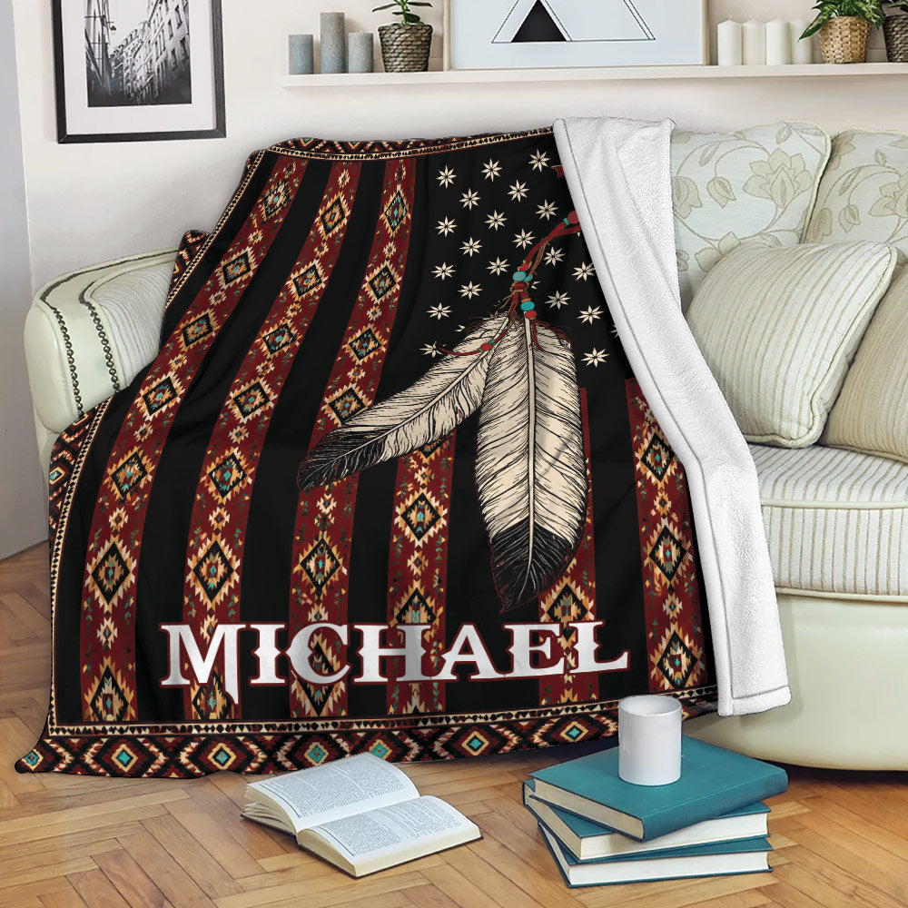 American Native-inspired throw blanket displayed on a sofa with feather artwork and patterned geometric stripes