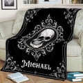 Close lifestyle view of a black skull blanket with vintage gothic scrollwork on a couch