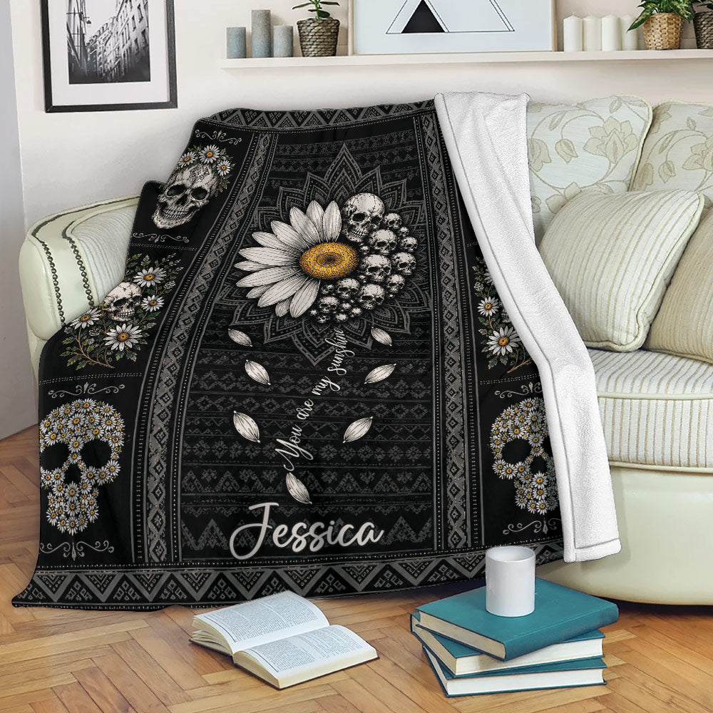 Floral skull throw blanket draped over a sofa with daisy wreaths and gothic-inspired black artwork