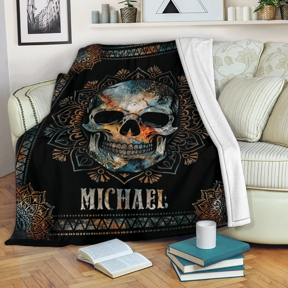 Skull throw blanket displayed across a sofa with bold black, blue, orange, and bronze artwork