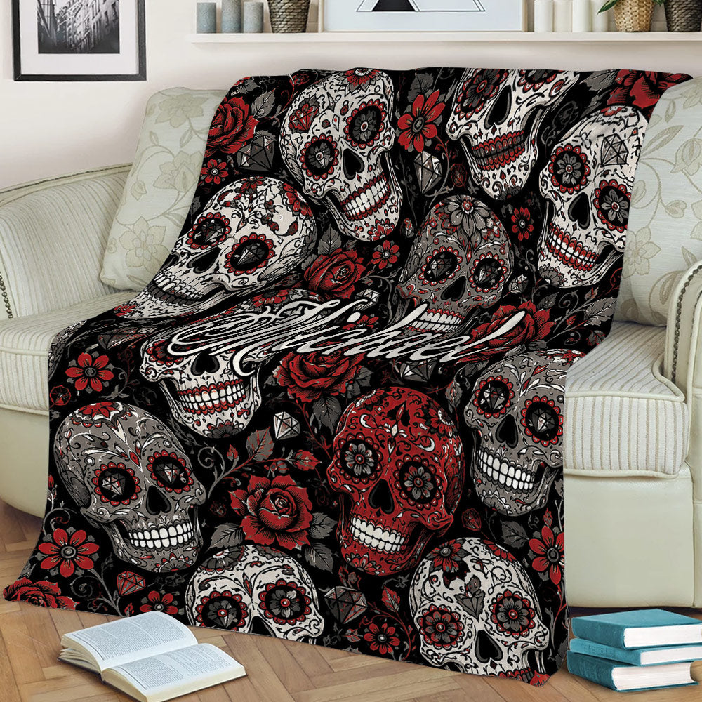 Gothic skull throw blanket displayed on a sofa with floral sugar skull artwork in black, red, and gray