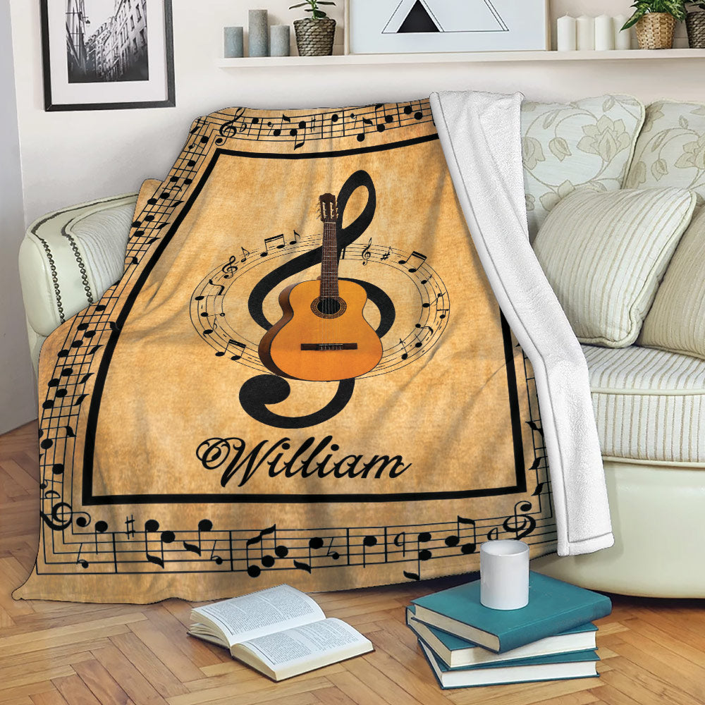 Acoustic guitar throw blanket displayed on a sofa with sheet music borders and warm tan musical artwork