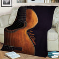 Large guitar blanket spread across a sofa with detailed strings, wood grain and dark contrasting artwork