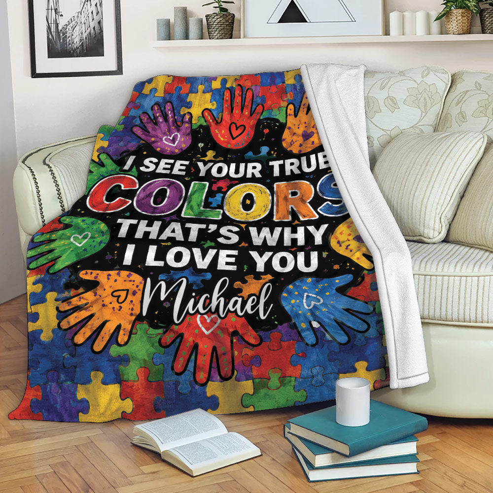 Autism awareness throw blanket displayed on a sofa with colorful puzzle pieces and handprint artwork