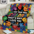 Colorful autism throw blanket draped over a sofa with puzzle pieces, handprints, and heartfelt artwork