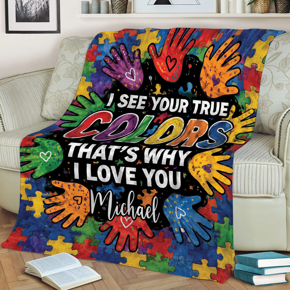 Colorful autism throw blanket draped over a sofa with puzzle pieces, handprints, and heartfelt artwork
