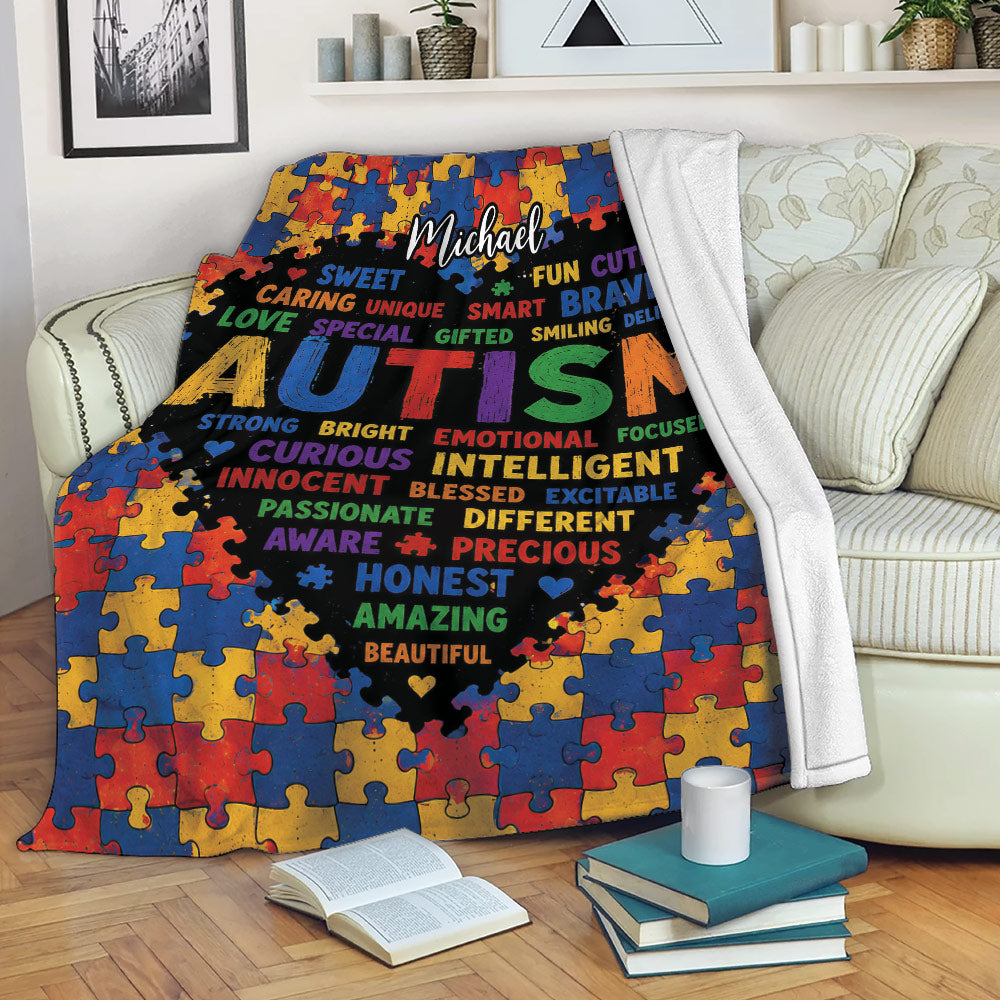 Colorful Autism throw blanket displayed on a sofa with puzzle-piece artwork and a bold black center design