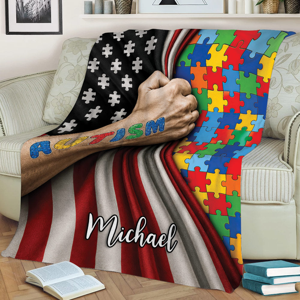 Close view of an autism throw blanket featuring multicolor puzzle pieces and dramatic red, black, and white stripes