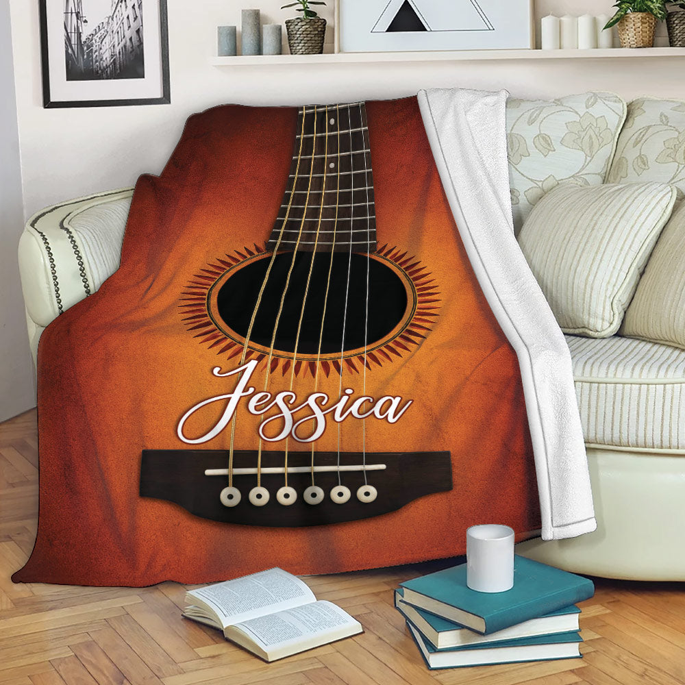Acoustic guitar throw blanket draped over a living room sofa with books and coffee