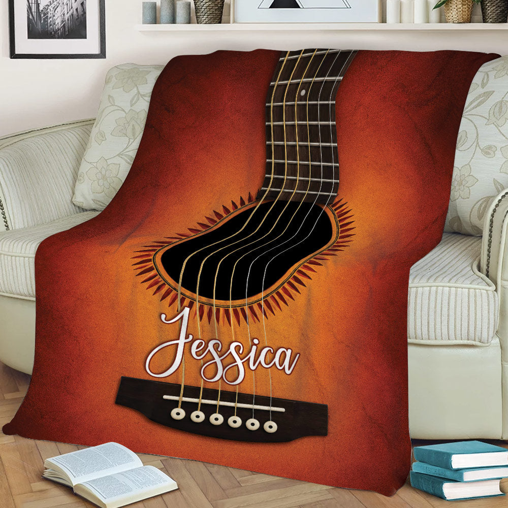 Close view of an acoustic guitar design on a throw blanket arranged across a sofa