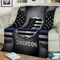 Police blanket draped over a sofa featuring a metallic shield, stars, and thin blue line design