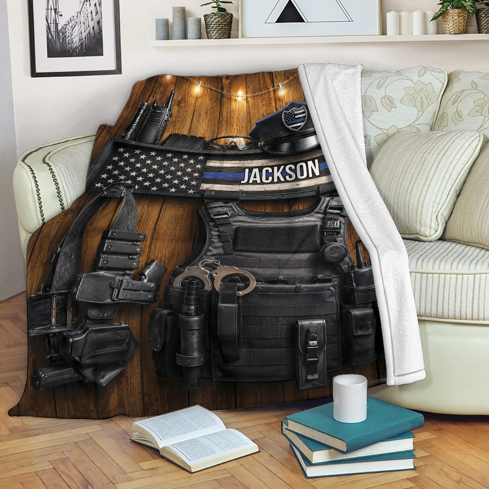 Police blanket displayed on a sofa with tactical equipment and rustic American flag design