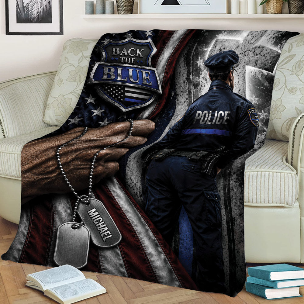 Close view of a police throw blanket featuring an officer, badge-inspired emblem, dog tags, and patriotic artwork