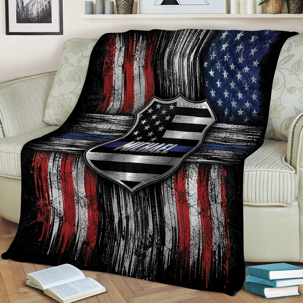 Thin blue line police blanket draped over a couch with patriotic badge and flag artwork