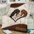 Horse blanket shown on a couch with detailed brown horse illustrations and leather-look accents