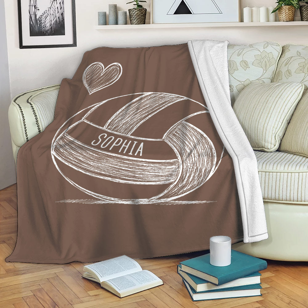 Brown volleyball throw blanket styled on a sofa with hand-drawn ball artwork and heart detail