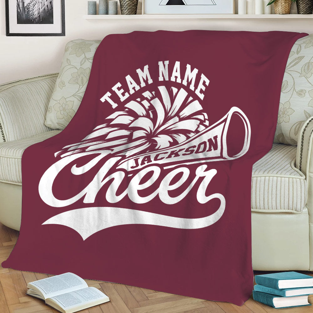 Maroon cheerleading blanket displayed on a sofa with large graphic cheer design