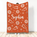 Orange cheerleading throw blanket featuring white pom-poms, megaphones, stars, and spirit-themed artwork
