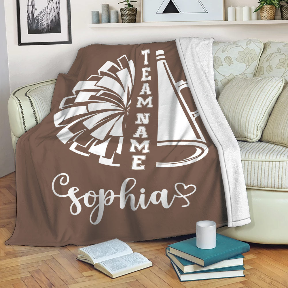 Cheerleading blanket draped over a sofa with bold pom-pom and megaphone design