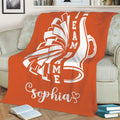 Orange cheerleading blanket displayed on a sofa with energetic pom-pom artwork