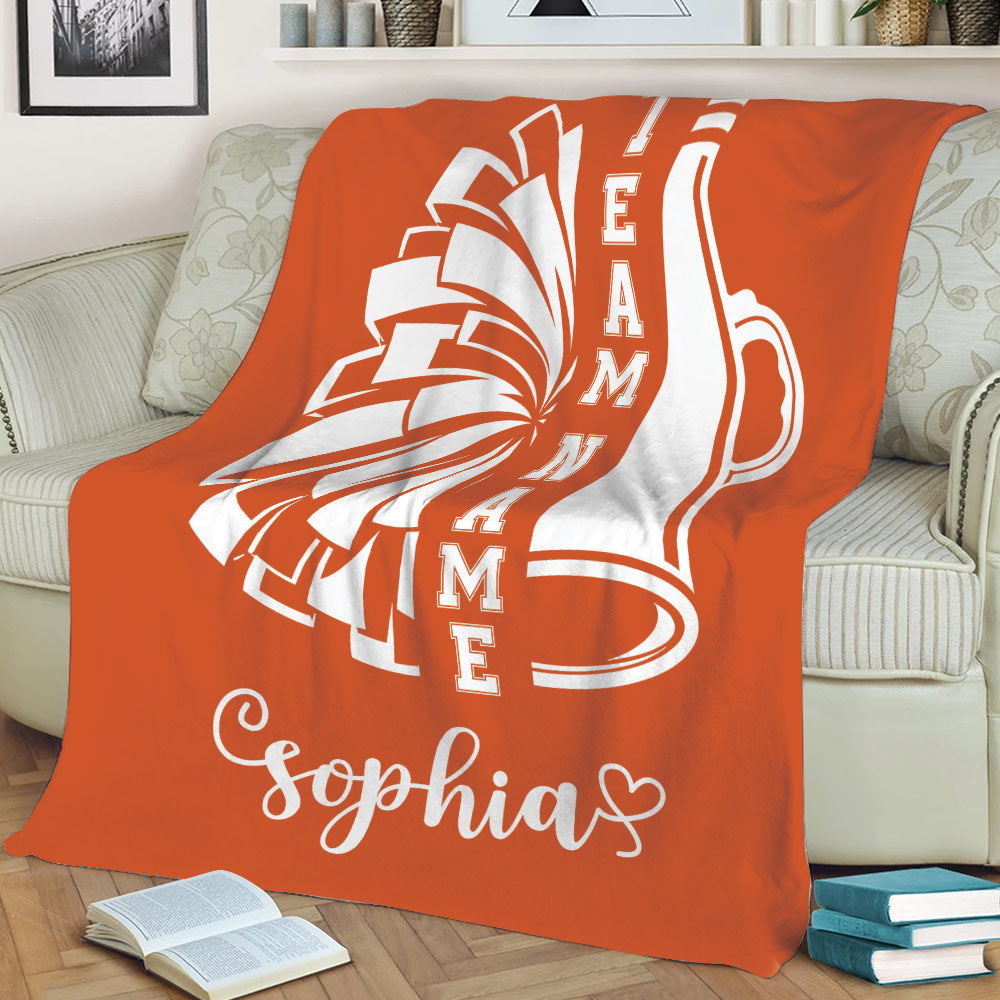 Orange cheerleading blanket displayed on a sofa with energetic pom-pom artwork