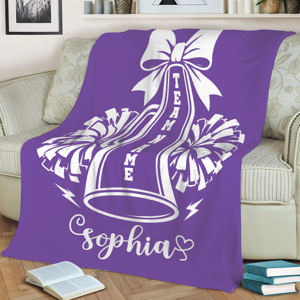 Purple cheerleading blanket draped over a sofa with bold megaphone and pom-pom artwork
