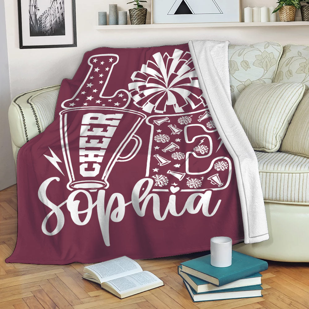 Maroon cheerleading throw blanket displayed on a sofa with megaphone and pom-pom artwork