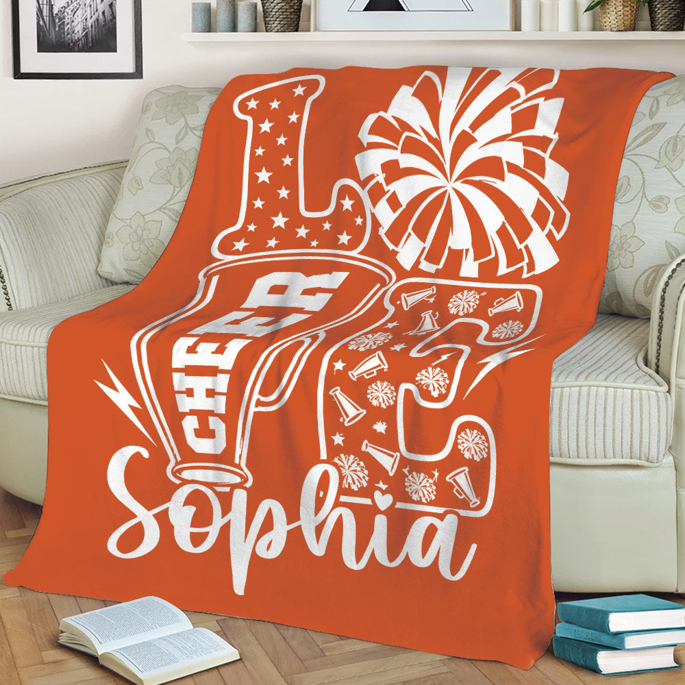 Orange cheerleading throw blanket on a sofa with bold megaphone and pom-pom artwork