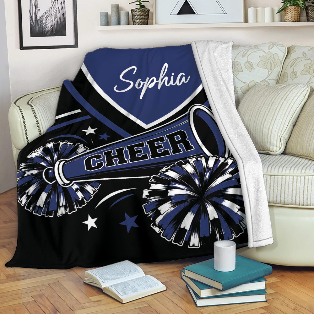 Navy cheerleading throw blanket draped over a sofa with pom-poms and megaphone artwork