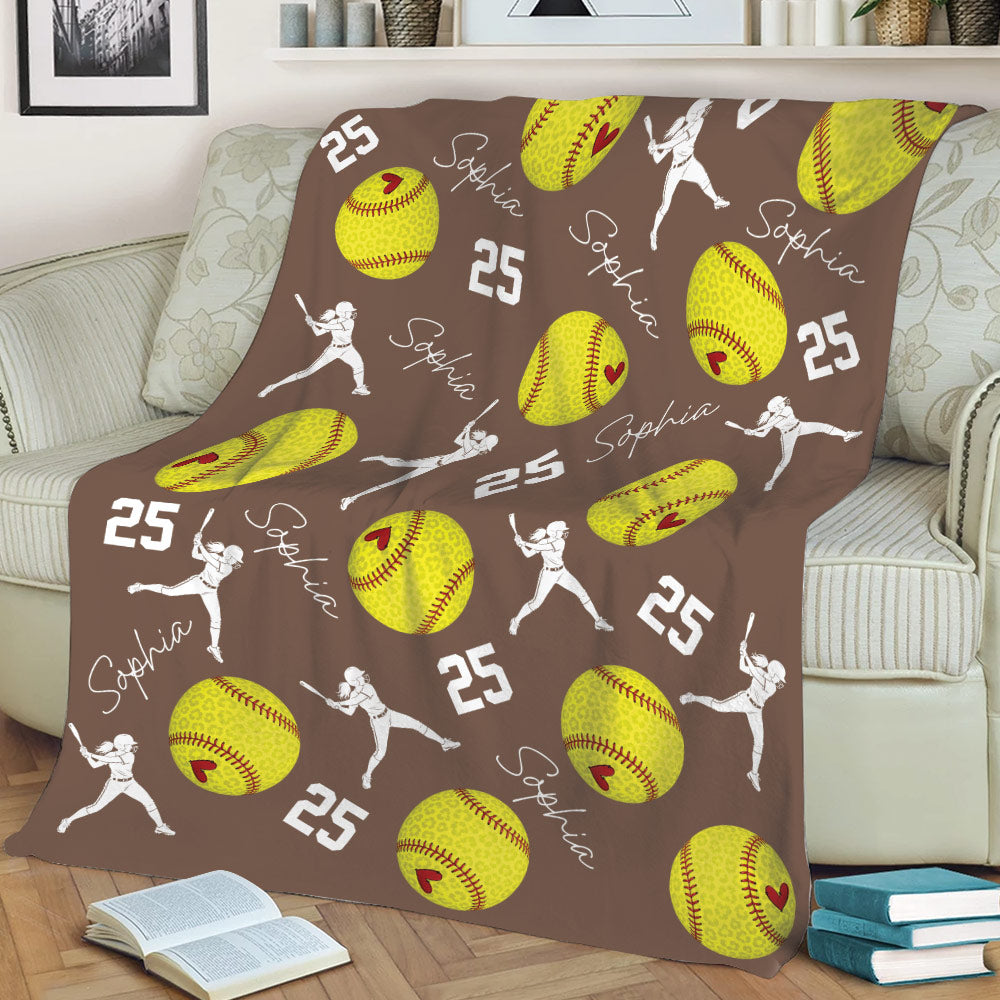 Brown softball throw blanket displayed on a sofa with yellow softball and player artwork