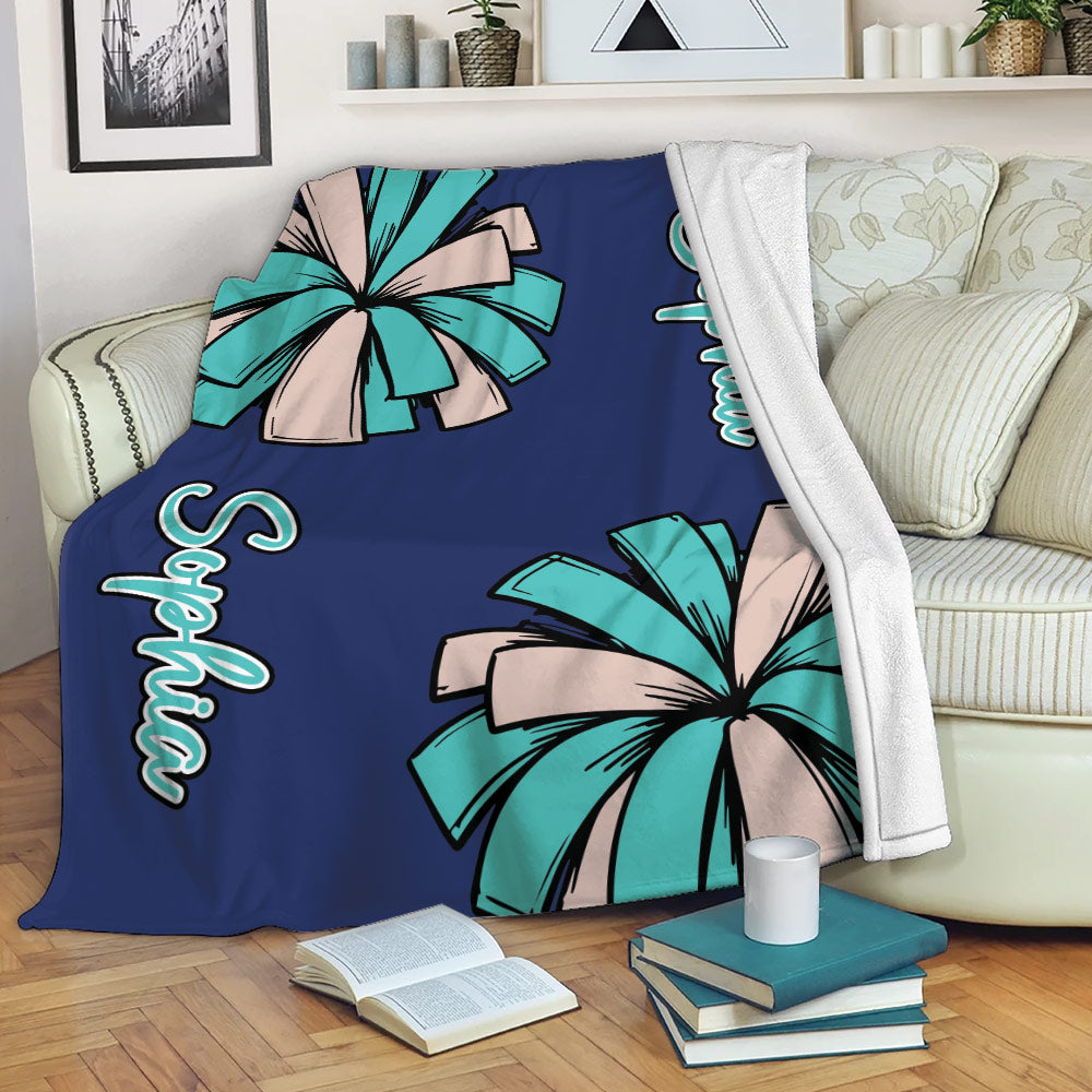 Cheerleading blanket draped over a sofa with teal and beige pom-pom artwork