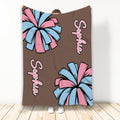 Cheerleading throw blanket featuring pink and light blue pom-poms on a brown background