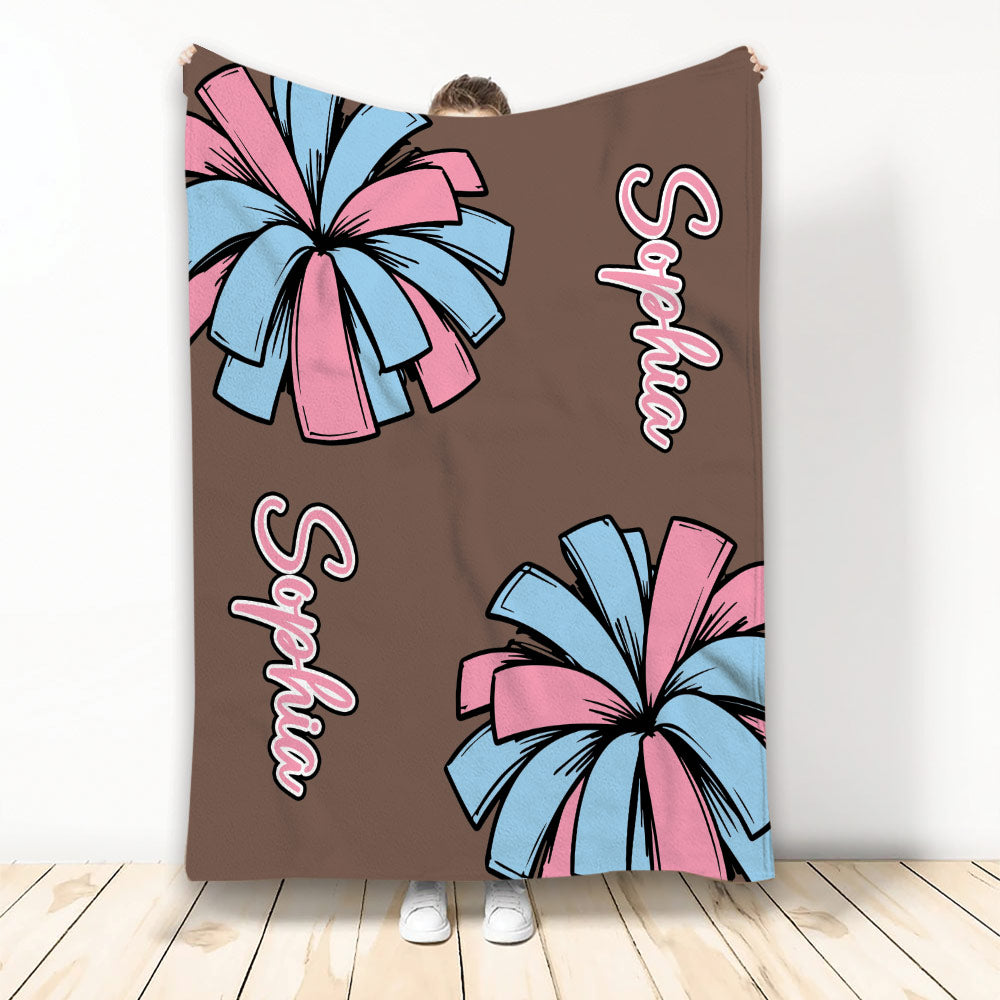Cheerleading throw blanket featuring pink and light blue pom-poms on a brown background