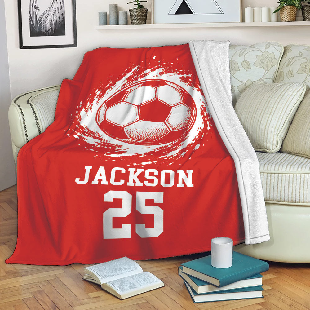 Red soccer blanket draped over a sofa with energetic ball artwork and sports-themed design
