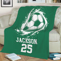 Green soccer blanket displayed on a sofa with dynamic soccer ball artwork and bold sports graphics