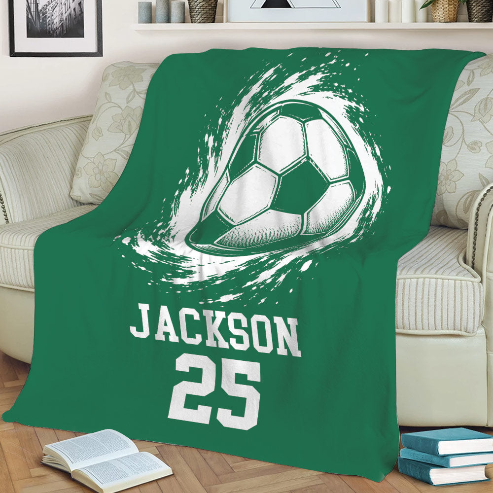 Green soccer blanket displayed on a sofa with dynamic soccer ball artwork and bold sports graphics