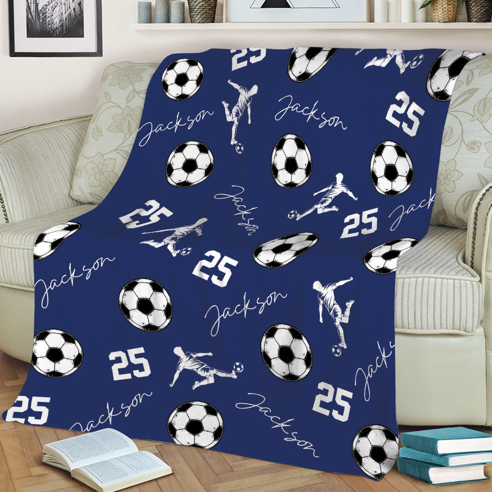 Navy soccer throw blanket draped over a sofa with soccer balls and active player artwork