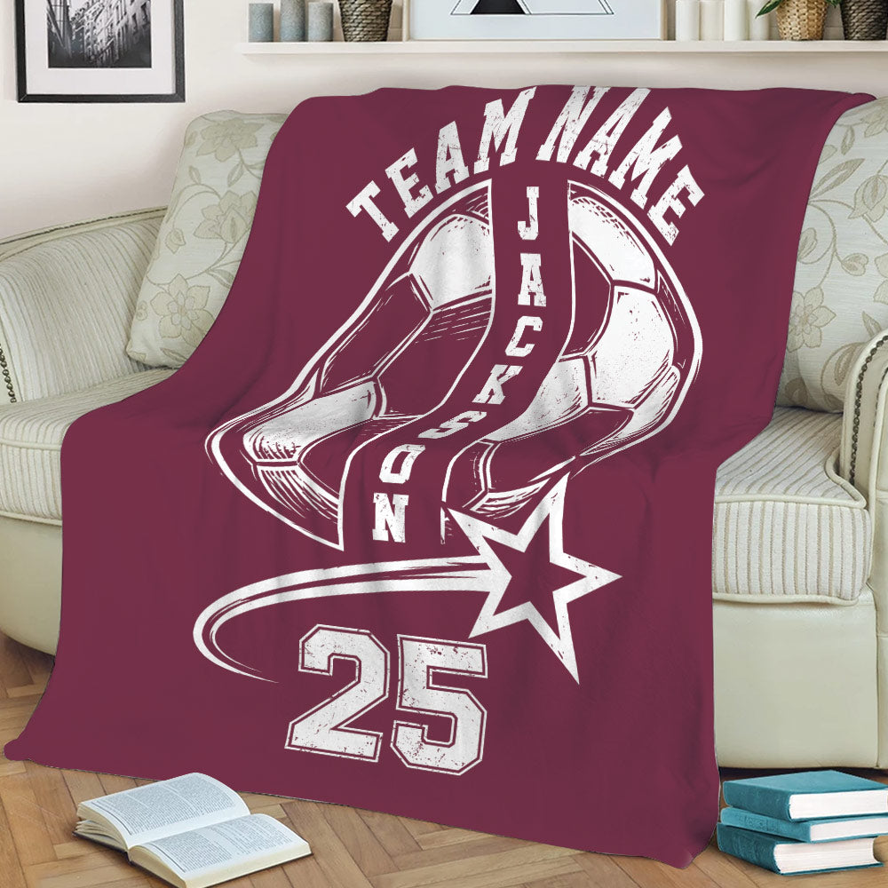 Maroon soccer throw blanket on a sofa featuring large soccer ball artwork and a bold athletic design