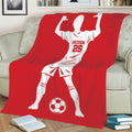 Red soccer throw blanket draped over a couch with a bold player silhouette and soccer ball artwork