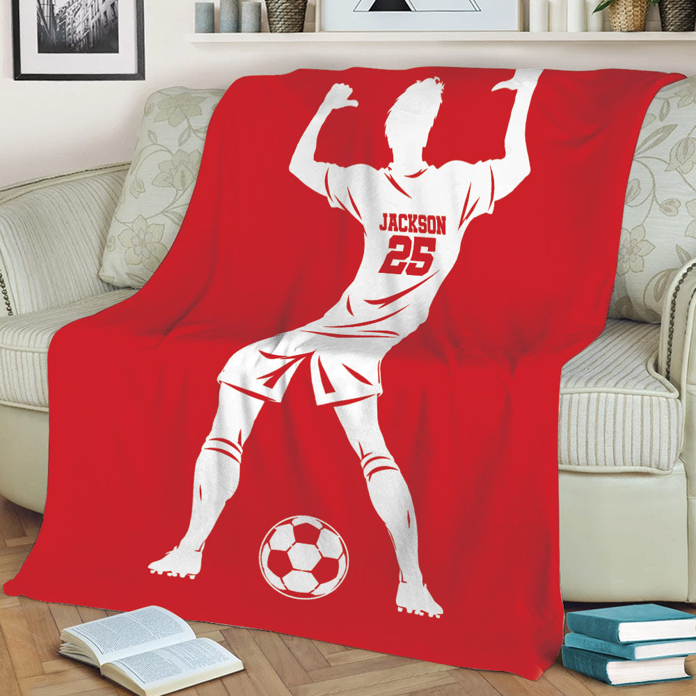 Red soccer throw blanket draped over a couch with a bold player silhouette and soccer ball artwork
