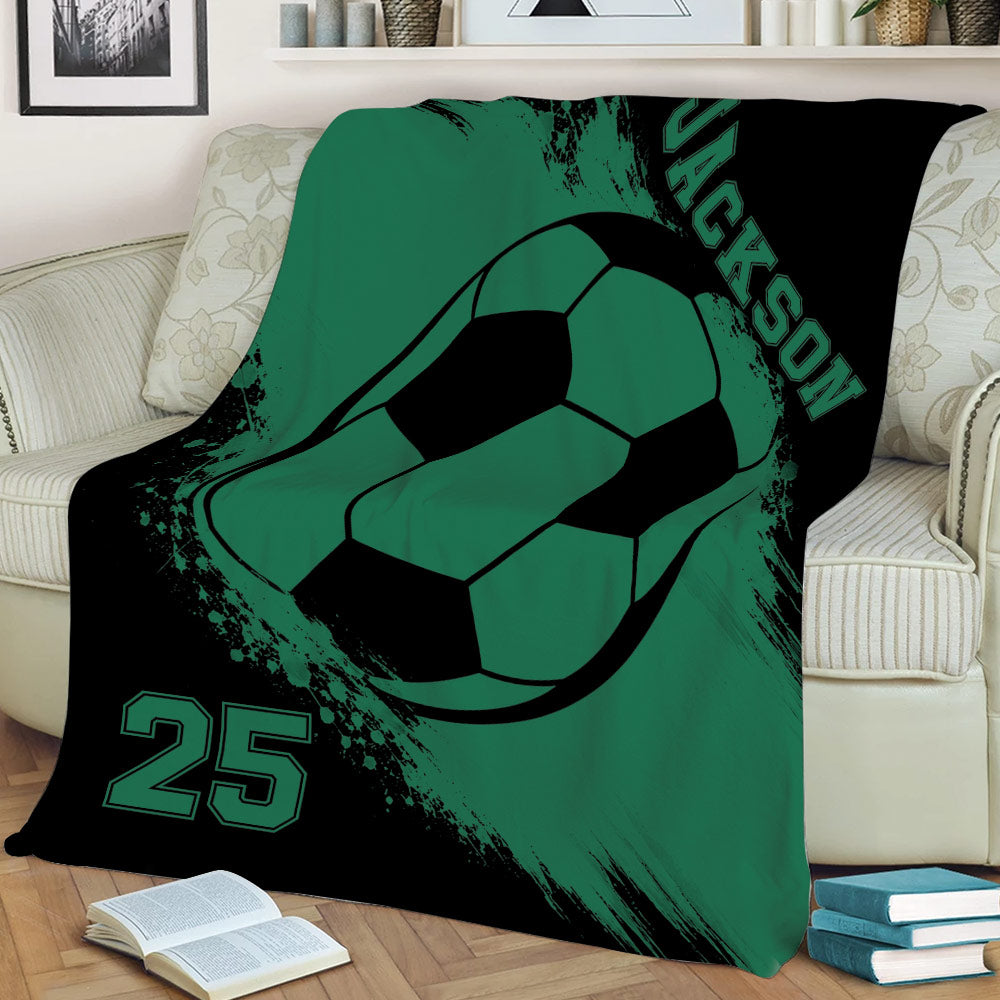 Green and black soccer blanket spread across a sofa with oversized soccer ball artwork