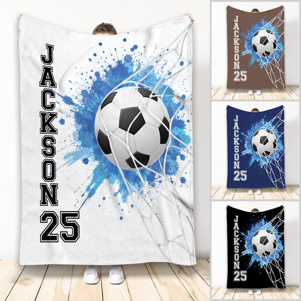 Soccer throw blanket with a ball in a goal net, blue paint splash artwork, and multiple color options