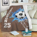 Soccer blanket draped over a sofa with blue splash artwork, a ball in a net, and bold vertical lettering