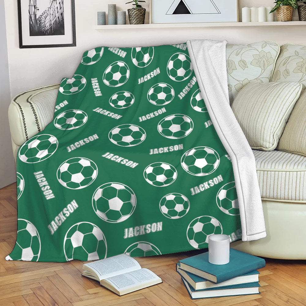 Green soccer throw blanket draped over a sofa with repeating soccer ball design