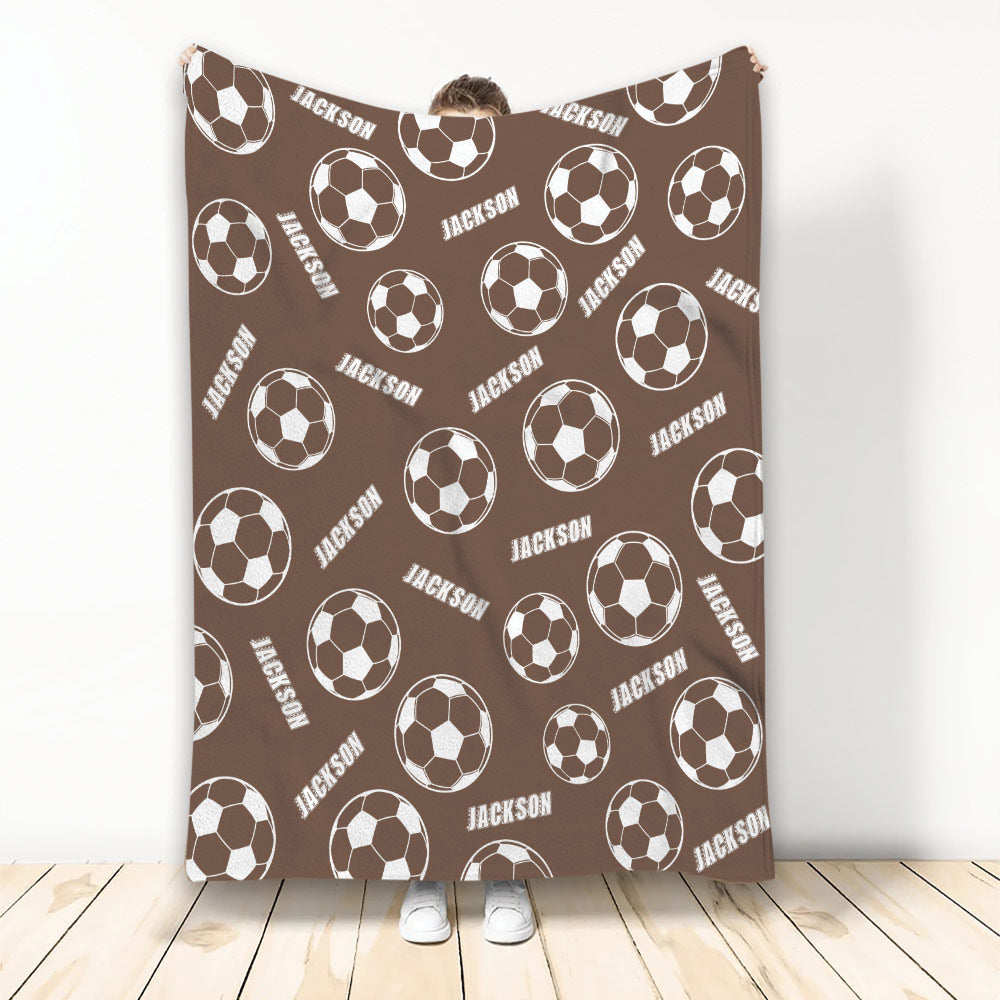 Brown soccer blanket displayed vertically with repeating white soccer ball artwork