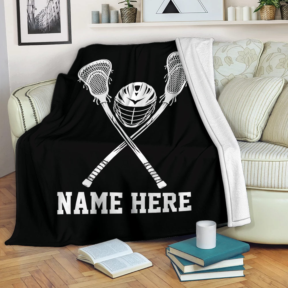 Black lacrosse throw blanket displayed on a sofa with crossed sticks and helmet artwork