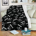 Black lacrosse throw blanket draped across a sofa with repeating sticks, helmets, and balls
